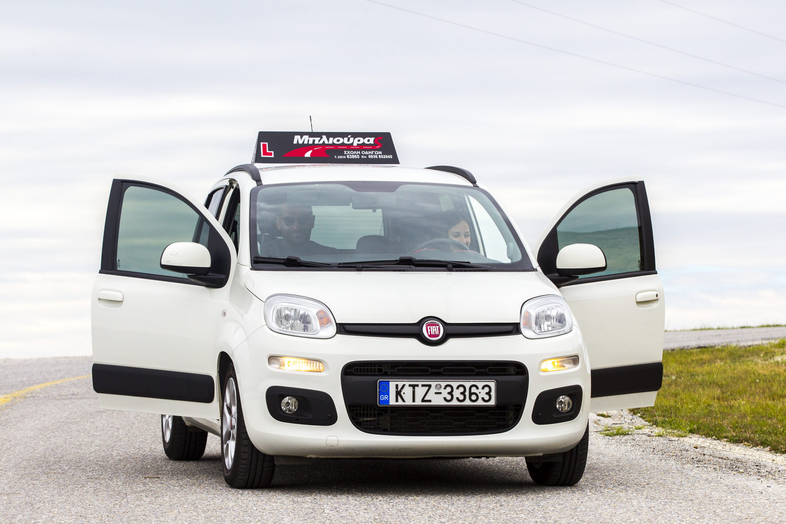 Εκπαιδευτής και μαθήτρια μπαίνουν στο εκπαιδευτικό αυτοκίνητο της σχολής οδηγών Μπλιούρας